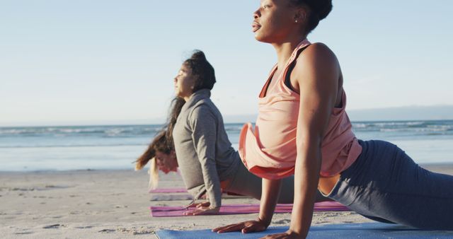 Group of diverse female friends practicing yoga, stretching at the beach. healthy active lifestyle, outdoor fitness and wellbeing.