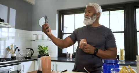 Senior Man Taking Selfie with Smoothie in Modern Kitchen