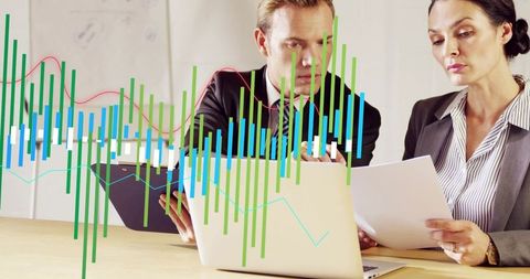 Business professionals analyzing financial data on laptop with overlaid charts and reports