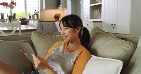 Young Asian Woman Enjoying Relaxation at Home with Tablet