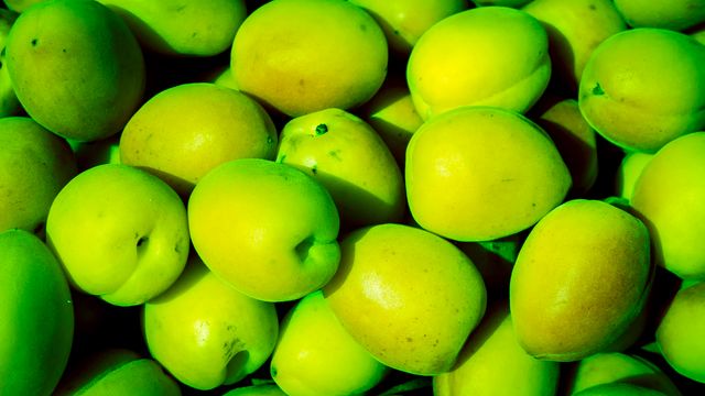 Bright green apples piled together in close-up view, emphasizing their freshness and vibrant color. Ideal for use in health and nutrition blog posts, grocery store advertisements, or organic food promotions.