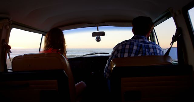 Rear view of couple driving van on roadtrip. Sunset sky in background 4k