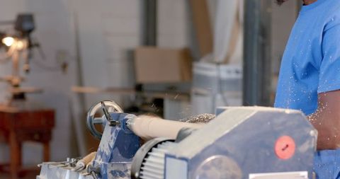 Carpenter using lathe to shape wood in workshop