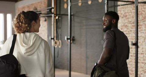 Friends chatting in modern industrial gym holding bags