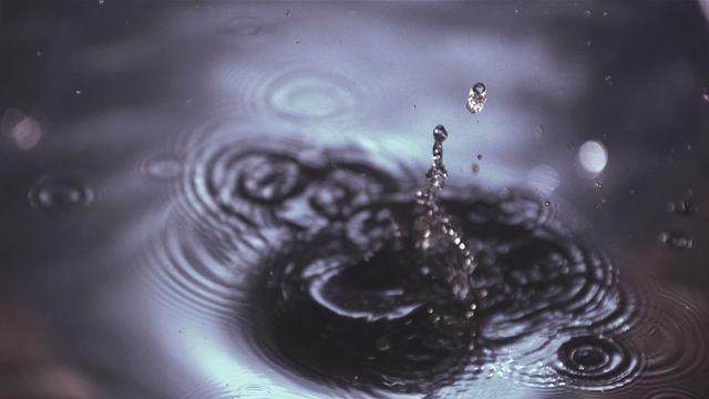 This visual captures dynamic imagery of a lime falling into water with high clarity and beautiful ripples forming upon the impact. Perfect for content related to refreshments, nature, dynamics of liquids, advertisements for beverages, or visual effects in presentations. The specific focus on the splash and ripples adds a dramatic yet elegant touch.