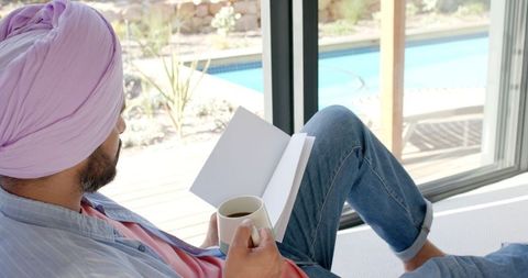 Relaxing Man in Turban Reading with Coffee by Window