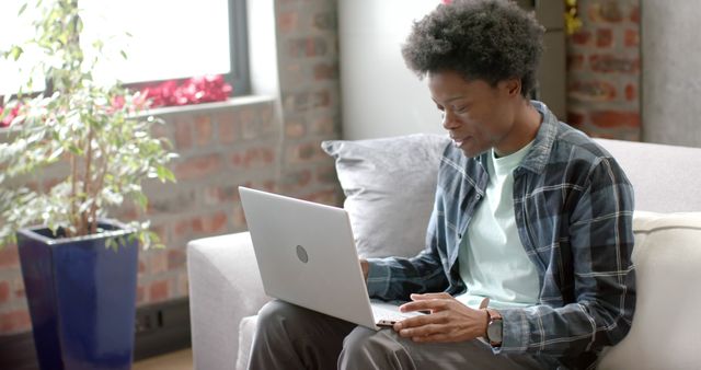 Focused Man with Afro Typing on Laptop in Cozy Home - Download Free Stock Images Pikwizard.com