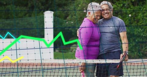 Senior couple embracing on tennis court with graph overlays