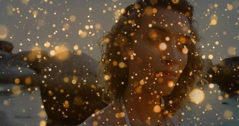 Woman reflecting in golden glow at rocky shoreline