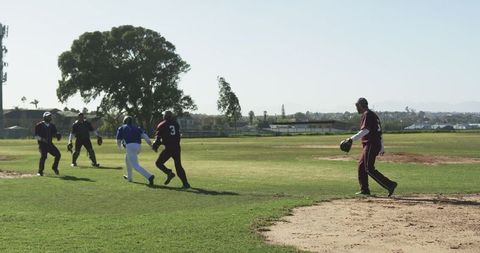 Men showing athleticism and teamwork during baseball game. Players running towards base while working together on field, indicating active participation. Useful for content focusing on sportsmanship, outdoor activities, or leisure sports.