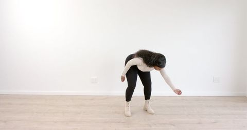 Woman practicing dance moves in minimalist room
