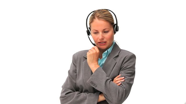 Businesswoman dressed in a grey suit using a headset, appearing thoughtful. Ideal for illustrating concepts related to customer support, professional communication, call centers, business environments, and women in professional roles. Suitable for websites, presentations, promotional materials, and career-related content.