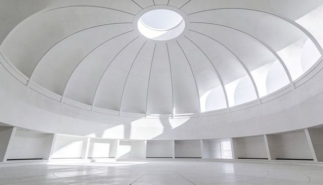 Minimal white rotunda featuring central oculus, ribbed dome, sweeping curvature, soft light