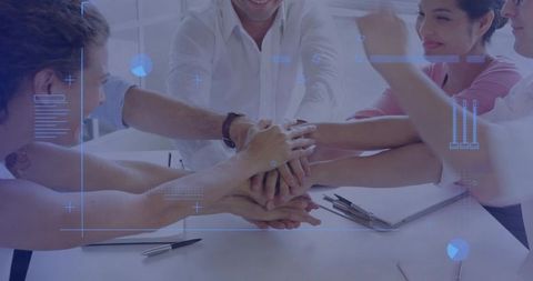 Diverse Business Team Stacking Hands Over Desk with Futuristic HUD Overlay for Innovation
