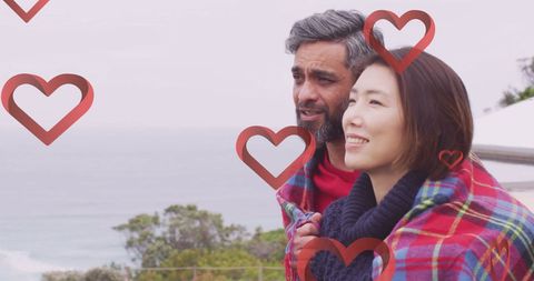 Diverse Couple Embracing on Balcony Surrounded by Hearts