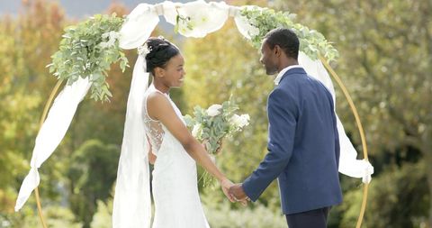 Joyful Bride and Groom Holding Hands in Garden Wedding Ceremony