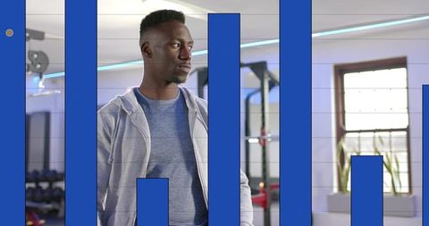 Focused man in grey hoodie standing in gym with blue bar graph overlay for training insights