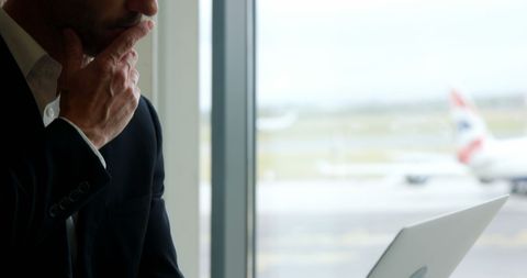 Thoughtful Businessman Uses Laptop for Work at Airport - Download Free Stock Images Pikwizard.com