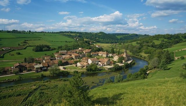 Winding river embracing quaint european village with church tower amid rolling green hills