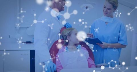 Pediatric dentist examining smiling child in dental chair with molecular overlay and assistant