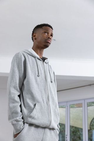 Pensive young man in casual grey sweatsuit at home