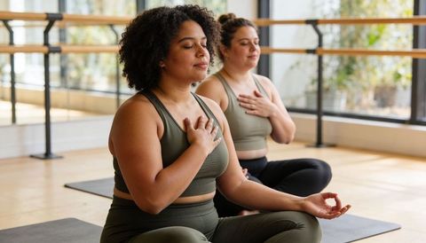 Two Women Practicing Breath Meditation in Yoga Studio Promoting Calm and Mindfulness