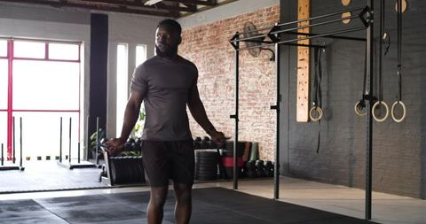 Athletic man skipping rope inside modern gym