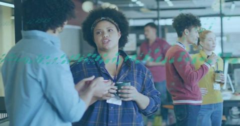 Young professionals chatting with coffee in modern open-plan office behind teal-dotted glass