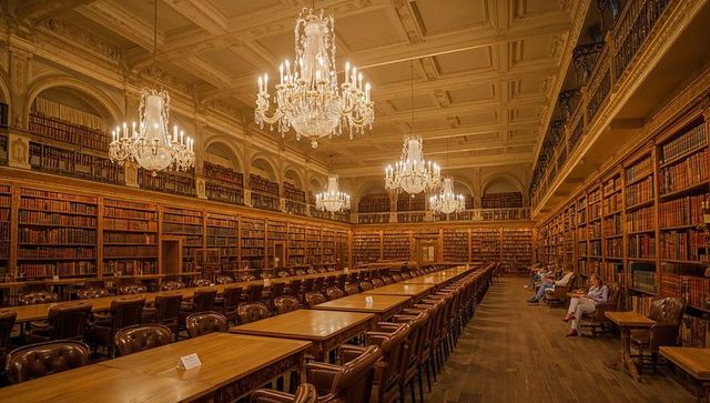 Grand historic library reading room with crystal chandeliers and long wooden tables
