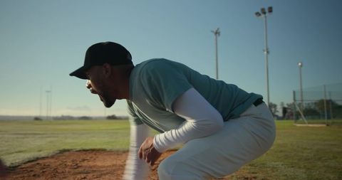 Crouching Baseball Coach Calling Play on Dirt Infield during Outdoor Practice Session
