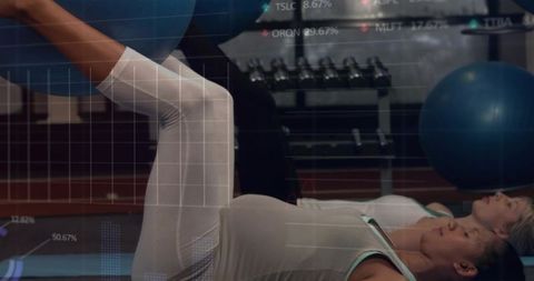 Partners strengthening core on mats using blue stability ball in gym studio