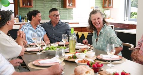 Cheerful Senior Friends Enjoying Gathering with Wine and Food at Home