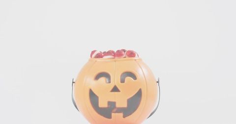 Smiling jack-o-lantern candy bucket filled with gummy sweets minimalist high-key
