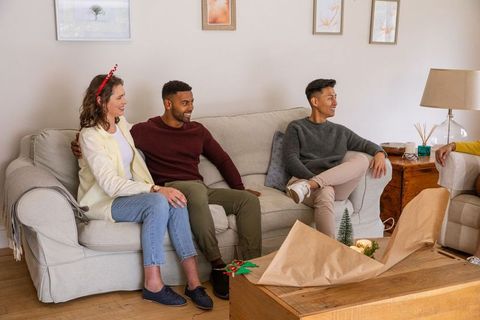 Diverse friends cozy gift wrapping in living room
