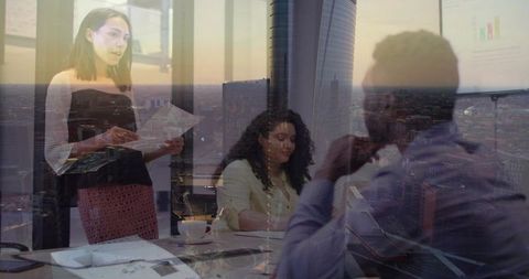 Executive team presenting strategy in glass boardroom with city skyline sunset reflections