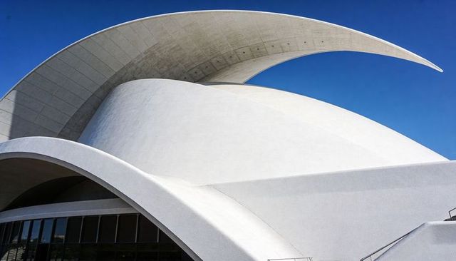 Sculptural Curved Concrete Canopy Over Modern Civic Auditorium Against Blue Sky