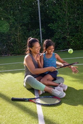 Mother teaching daughter tennis on sunny day outdoor sports fun