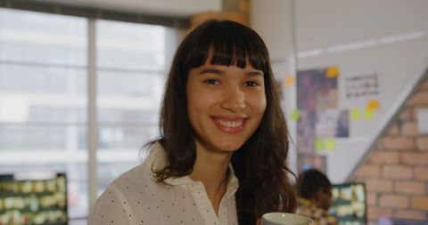Businesswoman Smiling with Coffee in Modern Office Environment