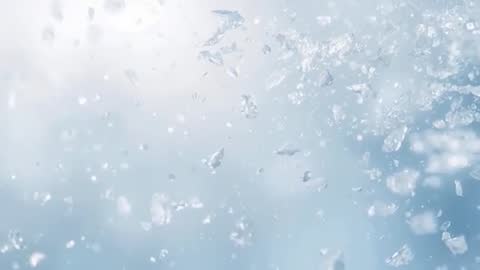 Macro video of crystalline shards drifting through pale blue bokeh, sparkling faceted motion