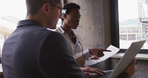 Co-workers Collaborating at Cafe with Laptop and Documents