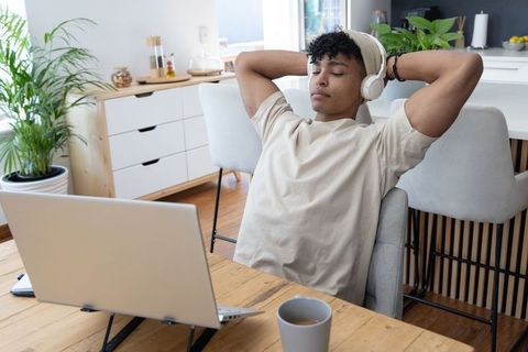 African american young man relaxing with wireless headphones at minimalist home workspace