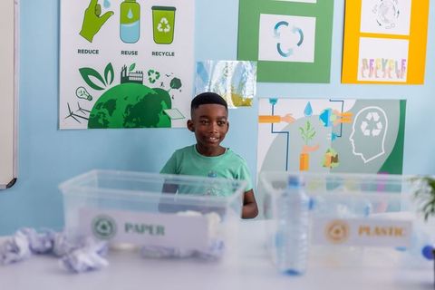 African american boy sorting recyclables in classroom for sustainability education