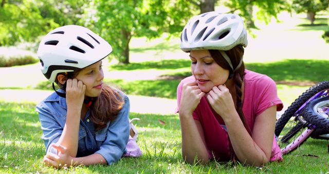 Mother and Daughter Relaxing on Grass with Bicycles and Helmets - Download Free Stock Images Pikwizard.com