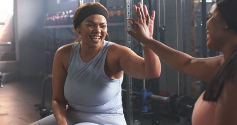 African American Women High-Fiving During Strength Workout on Bench with Kettlebells