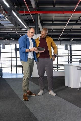 Two male coworkers reviewing tablet in modern industrial loft office