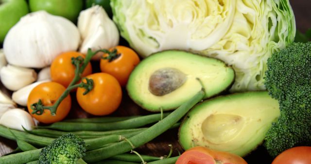 A variety of fresh vegetables, including tomatoes, avocados, broccoli, green beans, and garlic, are displayed, with copy space. These nutritious ingredients are essential for a healthy diet and are often used in vegetarian and vegan recipes.