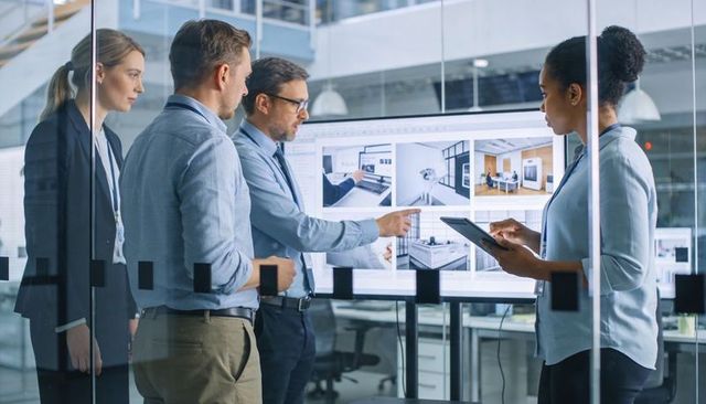 Design team reviewing interior renderings on large display, collaborating with tablet