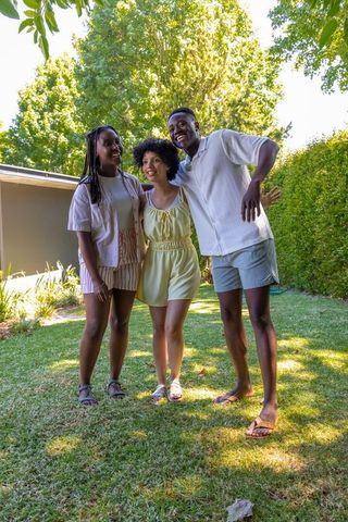 African american friends laughing and posing on sunlit backyard lawn in summer