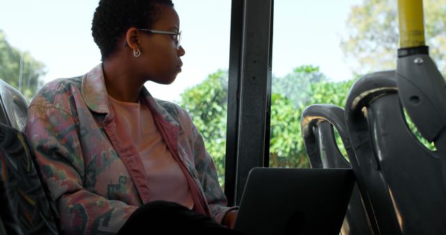 African american woman sitting in city bus using laptop. Communication, transport, city living and lifestyle, unaltered.