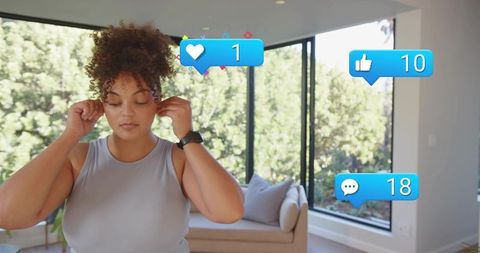Adjusting wireless earbuds in sunlit modern living room with social media notifications